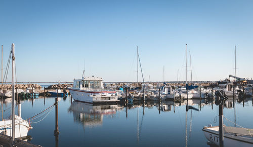 Boats moored at harbor against clear sky