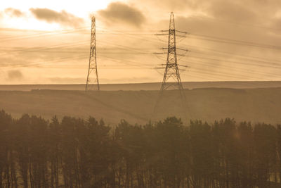 Silhouette electricity pylon against dramatic sky