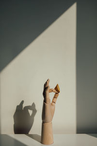 Close-up of hand holding paper against white wall