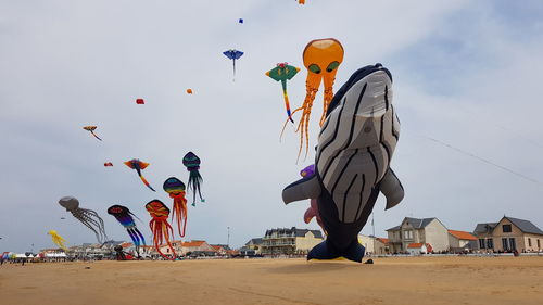 Multi colored balloons on beach against sky