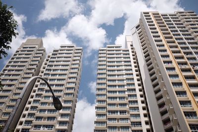 Low angle view of tall buildings against clouds