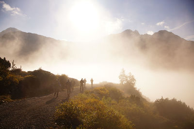 People walking on road against mountains during foggy weather at lechtal