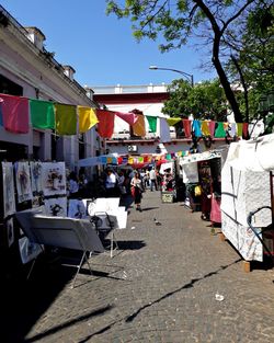 People on street market in city against clear sky