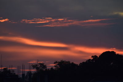 Silhouette trees against dramatic sky during sunset