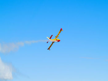 Low angle view of airplane flying against clear blue sky