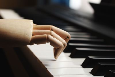 Cropped image of wooden statue on piano keys