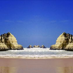 Rock formation on beach against clear blue sky