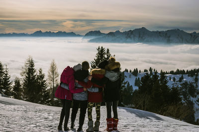 Rear view of people walking on snow covered mountain against sky