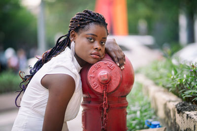 Portrait of young woman by fire hydrant in city