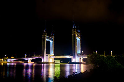 Illuminated bridge over river at night