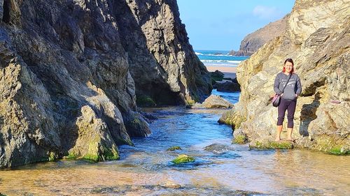 Woman standing on rock formation in water