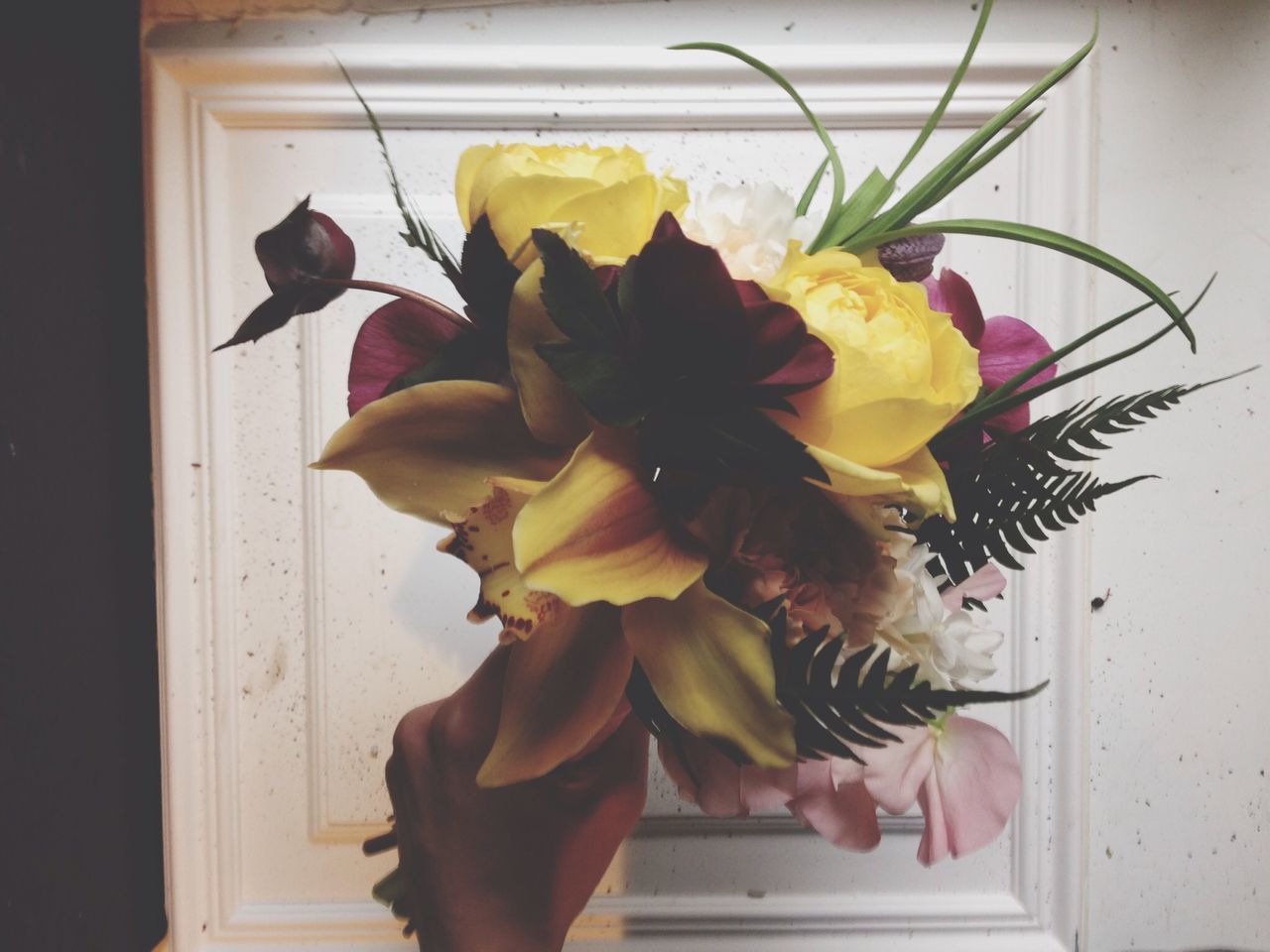 flower, indoors, one person, vase, wall - building feature, freshness, petal, flower head, yellow, holding, fragility, leaf, home interior, close-up, rose - flower, bouquet, creativity, wall, window, art