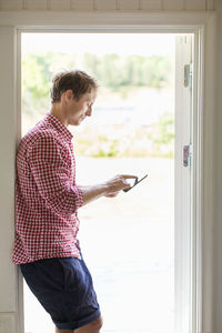 Profile shot of man using digital tablet at doorway