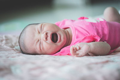 Baby girl crying while lying on bed