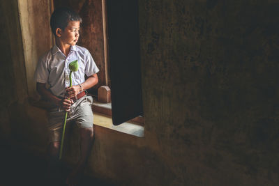 Boy looking through window at home