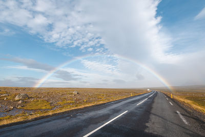 Road amidst field against sky