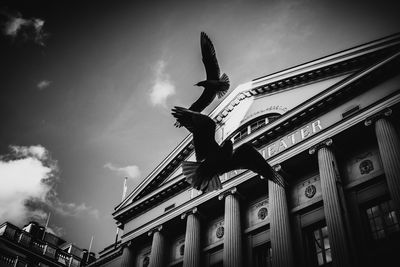 Low angle view of statue by building against sky