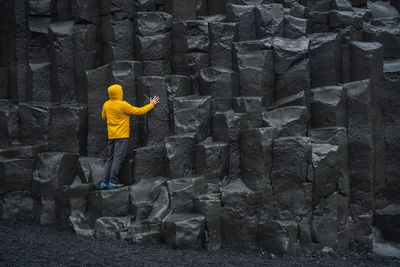 Rear view of man standing by stone wall