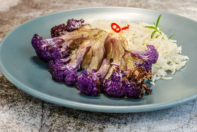 Purple cauliflower in a white baking dish in the oven