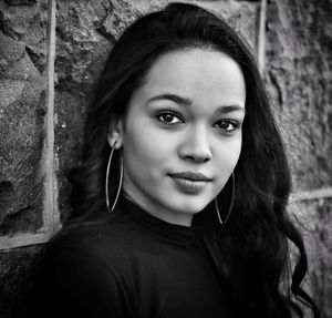 Close-up portrait of a young woman against wall