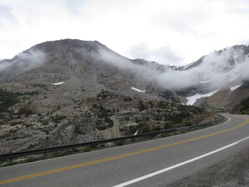 Road by mountains against sky