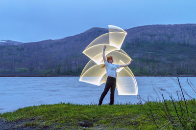 Woman making lighting paintings by lake