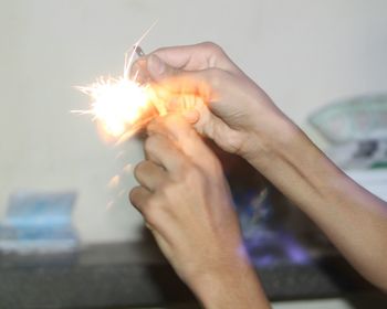 Cropped image of hand holding lit candle