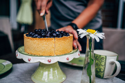 Midsection of person prepairing cake on table