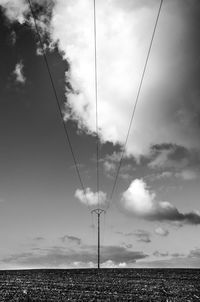 Low angle view of electricity pylon on field against sky