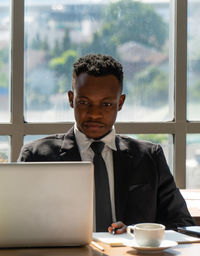 Businessman using laptop while sitting at desk in office