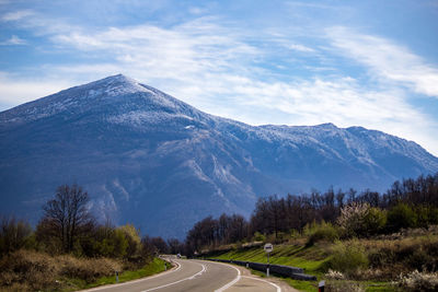 Road by mountains against sky