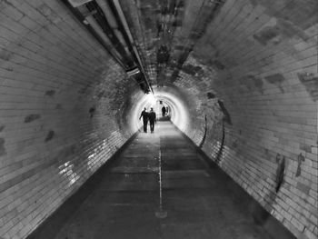 Rear view of woman walking in tunnel