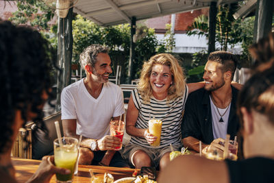 Happy woman enjoying smoothie with friends sitting at wellness resort