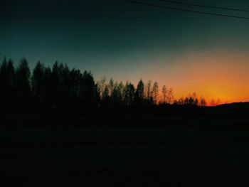 Silhouette trees against clear sky at sunset