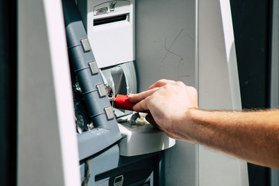 Cropped hand of man breaking atm machine