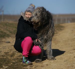 Woman crouching with dog on field