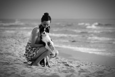 Full length of woman with dog on beach