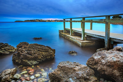 Scenic view of pier over sea against cloudy sky