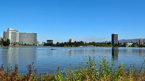 Buildings by lake against blue sky