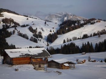 Houses on snow covered landscape against sky