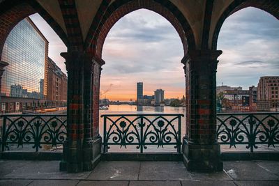 View of bridge and buildings against cloudy sky