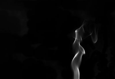 Close-up of burning candle against black background