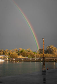 Scenic view of rainbow over river against sky