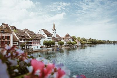 Scenic view of river by buildings against sky