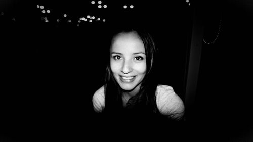 Close-up portrait of smiling woman in darkroom