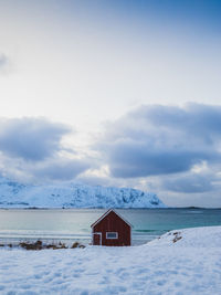 House on snow covered land against sky