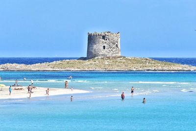 People swimming in sea against clear blue sky