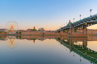 Bridge over river in city against clear sky