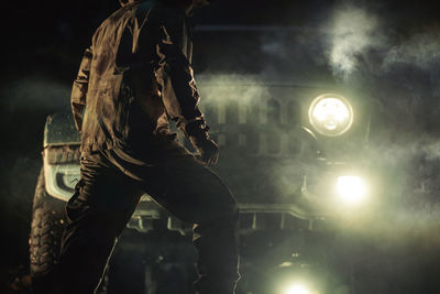 Low angle view of man standing against illuminated nightclub