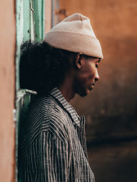 Side view of man leaning on wall while looking down